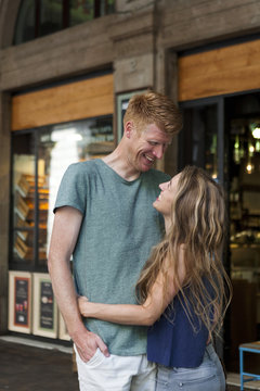 Happy couple standing in front of a coffee shop looking at each other
