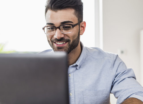 Smiling businessman with laptop in office