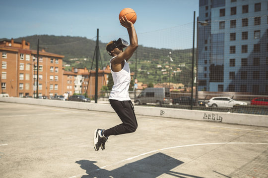 Young man playing basketball with virtual reality glasses on