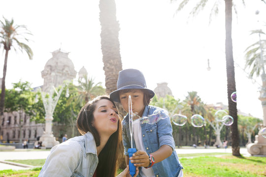 Mother and son blowing soap bubbles in park