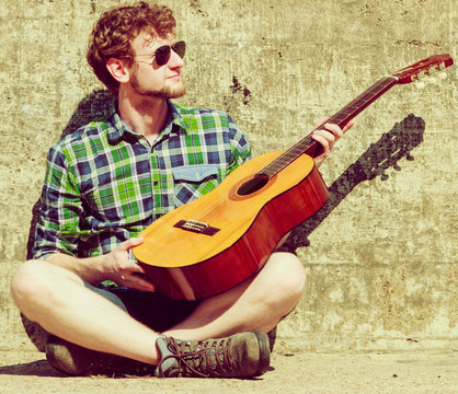 Young bearded hipster man with guitar outdoor