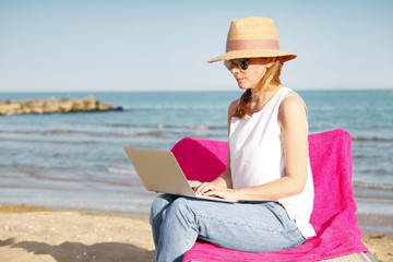 Woman working on laptop on the beach