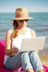 Woman working on laptop on the beach