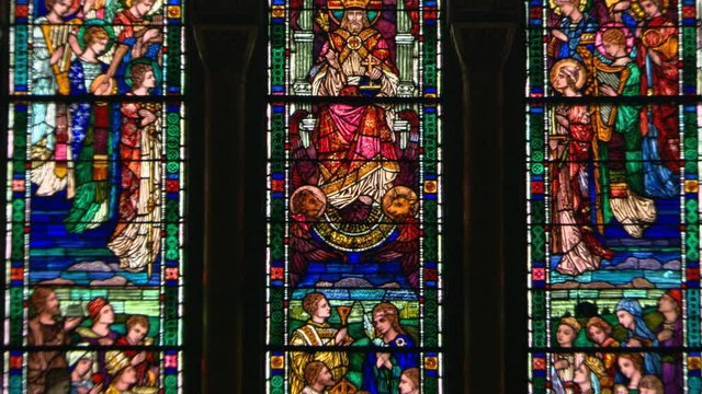 Zoom-out from a stained glass window to reveal a similar window on either side