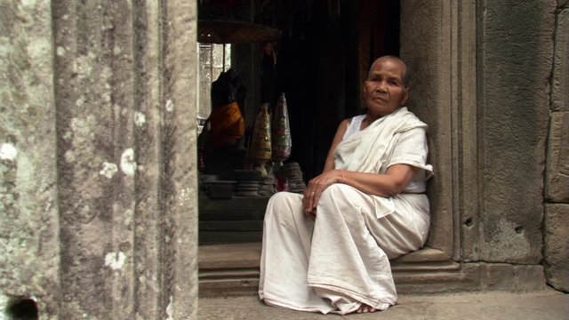 Cambodian woman with shaven head seated in doorway