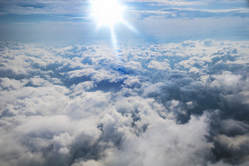 Clouds, sun and sky as seen in window of an aircraft