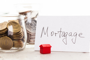 Mortgage concept by model house with coins