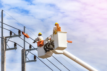 Electricians repairing wire of the power line on basket hydraulic platform