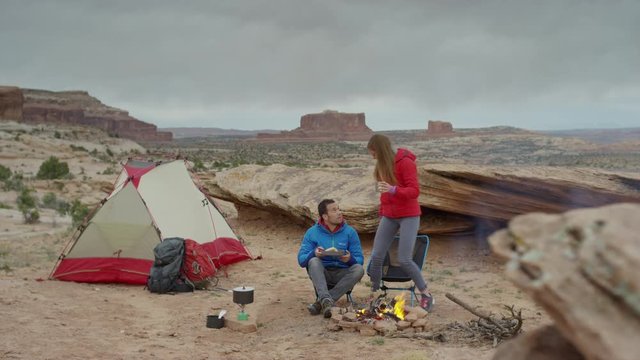 Wide panning shot of couple at campfire in desert / Moab, Utah, United States