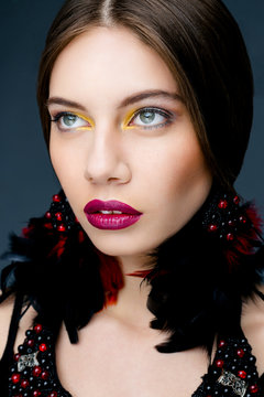 Portrait of beautiful woman with bright makeup red lips and feather earings