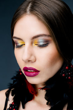 Portrait of beautiful woman with bright makeup red lips and feather earings