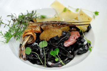 Tasty Italian food.
Fettuccine with the addition of cuttlefish ink sauce and pike caviar on a white plate.
Restaurant supply.