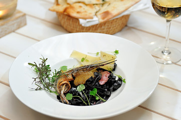 Tasty Italian food.
Fettuccine with the addition of cuttlefish ink sauce and pike caviar on a white plate.
Restaurant supply.