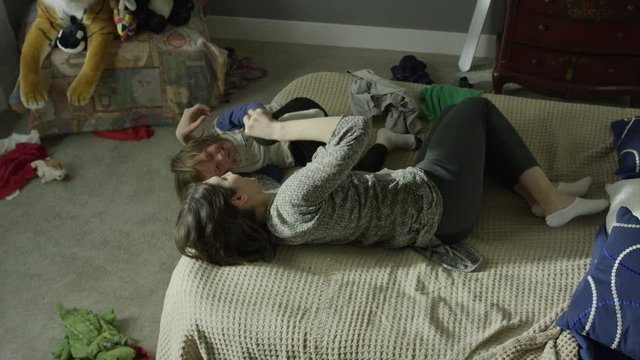 Medium high angle panning shot of mother tickling son on bed / Cedar Hills, Utah, United States