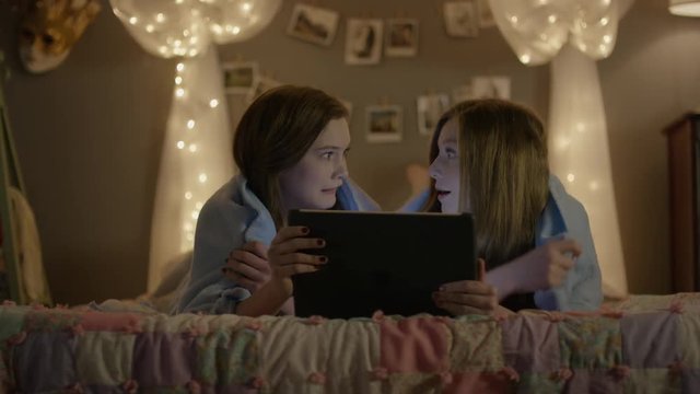 Medium shot of teenage girls watching scary movie during storm / Cedar Hills, Utah, United States