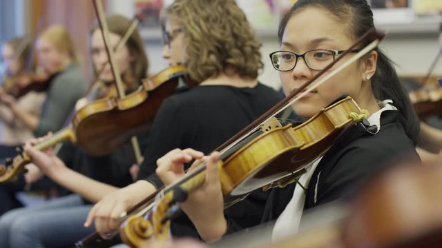 Medium shot of teenage girls playing violins in orchestra practice / American Fork, Utah, United States