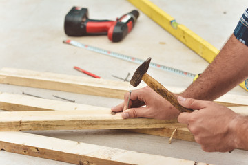 Man hands drive nail with a hammer in wooden