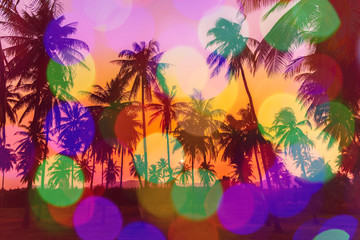 Silhouette coconut palm trees on beach with colorful bokeh at sunset. Vintage tone.