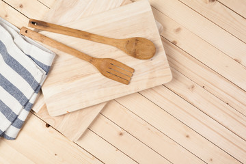 Wooden spoons and other cooking tools with blue napkins on the kitchen table.