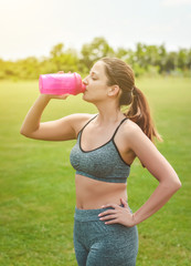 A young girl who participates in sport at the stadium drinking water