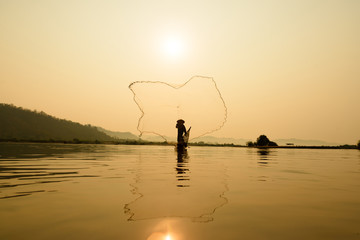 fisherman on boat with sunrise background, the Mekong River in Thailand
