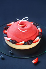 Contemporary Summer Berry Mousse Cake covered with red velvet spray and decorated with fresh...