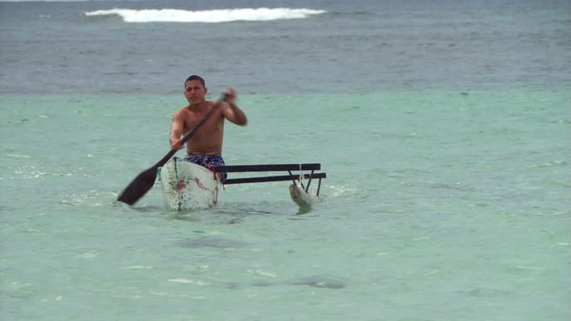 Samoan man paddling an outrigger canoe to shore