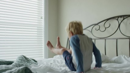 Medium panning slow motion shot of boy jumping on bed / Cedar Hills, Utah, United States - Powered by Adobe