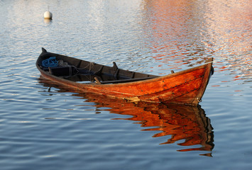Wooden rowboat in warm evening light partly filled with water