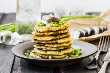 Fried potato pancakes with herring on a dark background