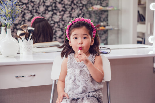 Little girl in front of the mirror doing her makeup