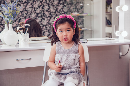 Little girl in front of the mirror doing her makeup