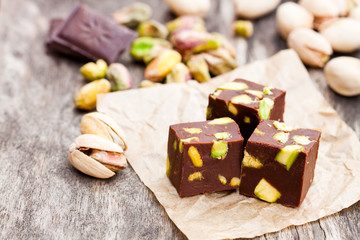 Dark  chocolate cubes with pistachios on wooden background