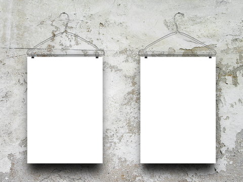 Close-up of two square blank frames hanged by clothes hanger against gray weathered concrete wall background
