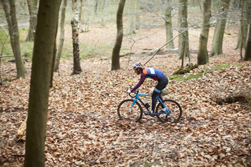 Young man cross-country cycling through a forest