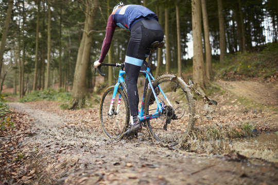 Cross-country cyclist riding in mud, low angle back view