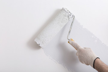 Close up of painter hand painting a wall grey with paint roller