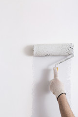 Close up of painter hand painting a wall grey with paint roller