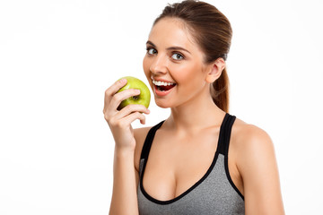 Portrait of young beautiful sportive girl holding apple over white background.