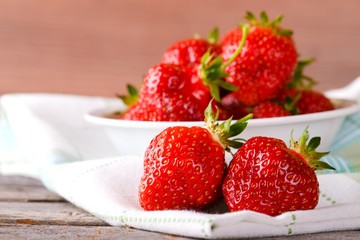 Red fresh strawberries on cloth in front of bowl