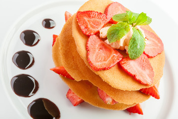 waffles with caramel sauce, whipped cream and strawberries isolated on white background