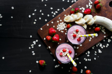 Strawberry and banana smoothie in the glass on black background