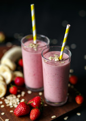 Strawberry and banana smoothie in the glass on black background