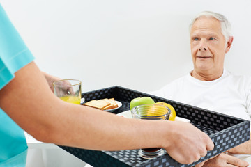Senior im Pflegeheim bekommt Frühstück ans Bett