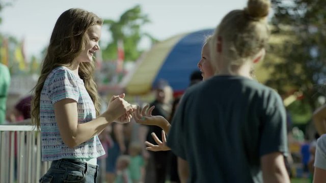 Medium shot of girls playing clapping game at funfair / Pleasant Grove, Utah, United States