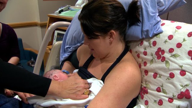 Zoom-in on newborn infant nursing at his mother's breast