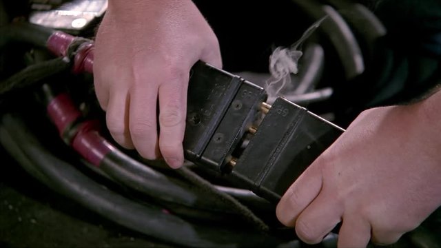 Close-up of hands plugging electrical cords together, followed by flash and smoke