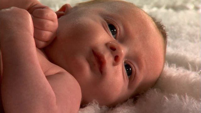 Close-up of blue-eyed baby lying on fuzzy blanket
