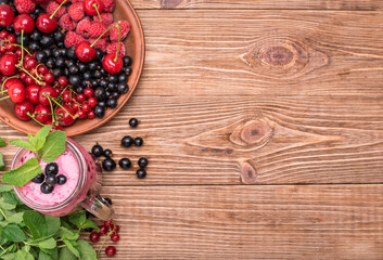 Fototapeta na wymiar Smoothies with fresh berries currants in glass jar on a wooden background.