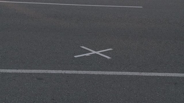 Zoom-in to white X on gray pavement